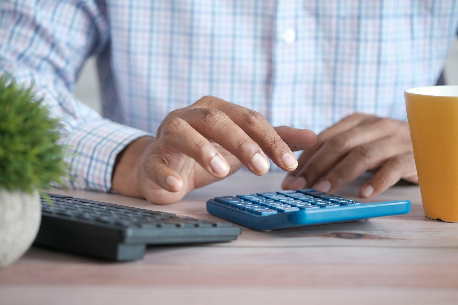 Pessoa usando calculadora em mesa de escritório para calcular pró-labore e distribuição de lucros