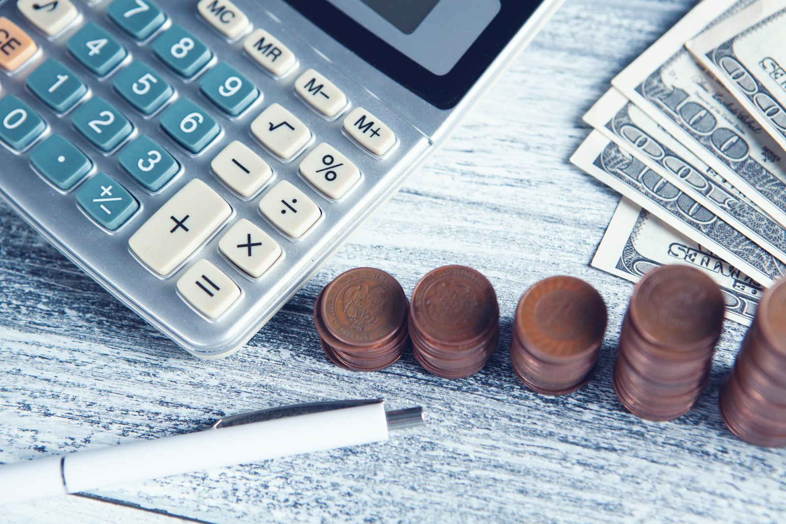 Calculadora, caneta e dinheiro sobre a mesa: como separar finanças pessoais e empresariais na PJ